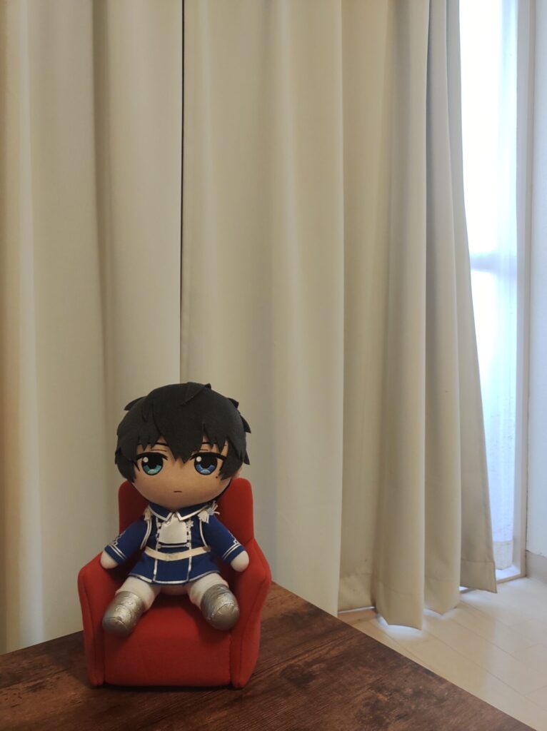 カーテンをバックにソファに座る恭二ぬい